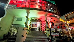 A hotel with a red and green facade, a staircase with yellow and black decorations, and a sign for the hotel and restaurant. - Hotel Datia Comfort Inn (Datia)