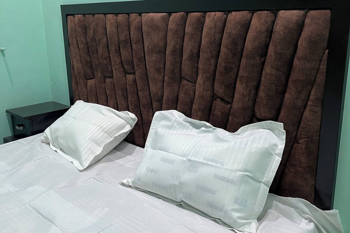 A bed with a headboard, two pillows, and a nightstand.