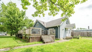 A two-story house with a deck, a front porch, and a fenced backyard.