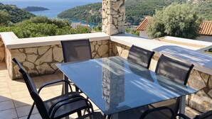 A glass-top table with four chairs, set against a stone wall with a view of a coastal landscape. - Villa Eleanor, Sivota Lefkada - 13 minute walk to the Bay.
Stunning Sea views. (Sivota Bay)