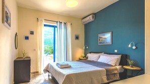 A bedroom with a bed, bedside tables, a nightstand, a window with curtains, an air conditioner, and a wall-mounted lamp. - Villa Eleanor, Sivota Lefkada - 13 minute walk to the Bay.
Stunning Sea views. (Sivota Bay)