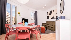 Ein modernes Wohnzimmer mit einem runden Tisch, roten Stühlen, einem Sofa und einem Fernseher.