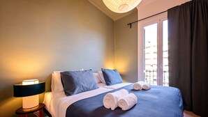 Ein ordentlich bezogenes Bett mit blauer Bettwäsche, einer Nachttischlampe und zusammengerollten Handtüchern auf dem Bett.