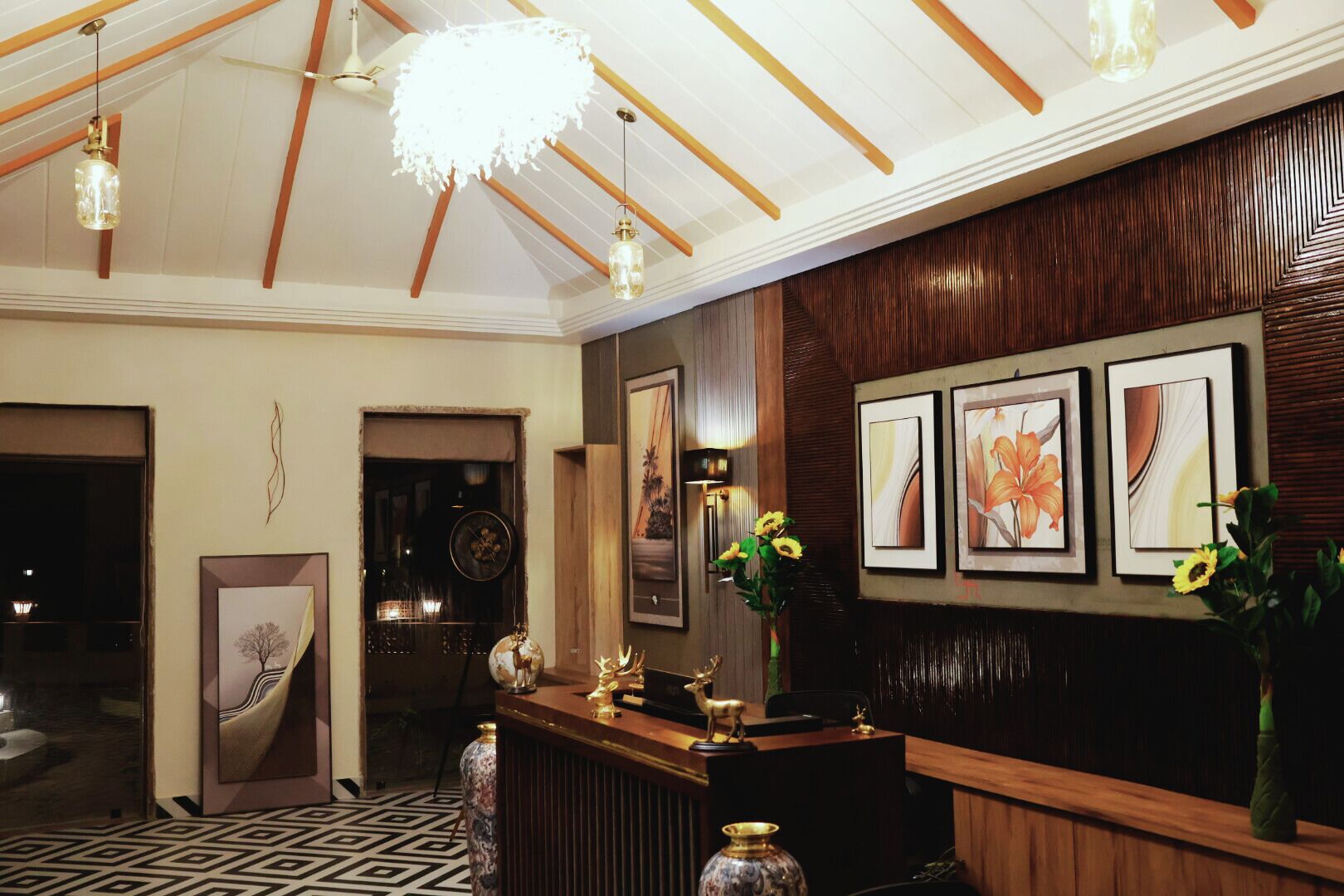 A reception area with a wooden reception desk, framed artwork on the wall, and a chandelier.