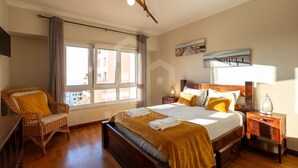 Une chambre à coucher avec un lit, une chaise, une table de chevet, une lampe et une fenêtre.