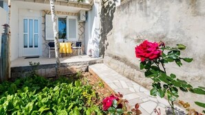 A courtyard with a white building, a yellow table, and a red rose.