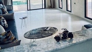 Una sala de estar moderna con un ventanal grande, un sofá, una mesita de centro y una motocicleta.