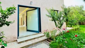 Un edificio moderno con un amplio escaparate de vidrio y escalones que conducen a un jardín con follaje y flores.
