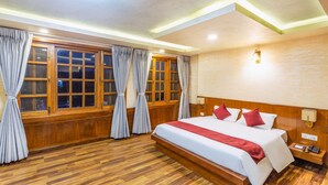 A hotel room with a large bed, wooden flooring, and a view through the window. - Hotel Nova Nook (Kathmandu)