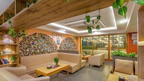 A modern lounge area with leather sofas, wooden tables, and a floral wall mural. - Hotel Nova Nook (Kathmandu)