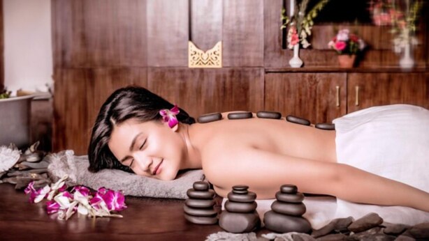A person receiving a back massage with stones and flowers on a wooden floor. - Hotel Nova Nook (Kathmandu)