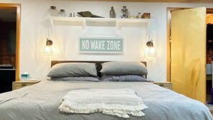 Un dormitorio con una cama, un letrero que dice 'NO WAKE ZONE' y un tragaluz.