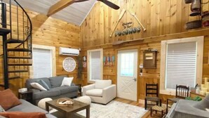 Interior acogedor de una cabaña con detalles de madera, una escalera en espiral, chimenea y decoración rústica.
