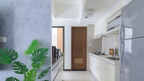 A modern kitchen with white cabinets, a stainless steel refrigerator, and a wooden door. - Taipei Main Station Modern Comfort 2B1b Living, Dining, Kitchen (Taipei City)