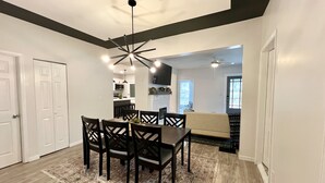 A dining area with a dark wood table and chairs, a patterned rug, and a modern ceiling light fixture.