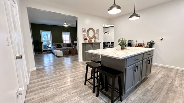 A spacious kitchen with a large island, dark wooden bar stools, and pendant lighting.