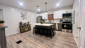 A modern kitchen with a central island, stainless steel appliances, and pendant lighting.