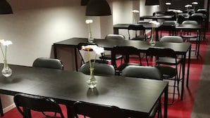 A conference room with multiple tables and chairs, black pendant lights, and a red carpet. - 11rum&kök  (Sandviken)
