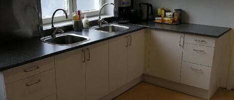 A kitchen with white cabinets, a black countertop, and a sink.