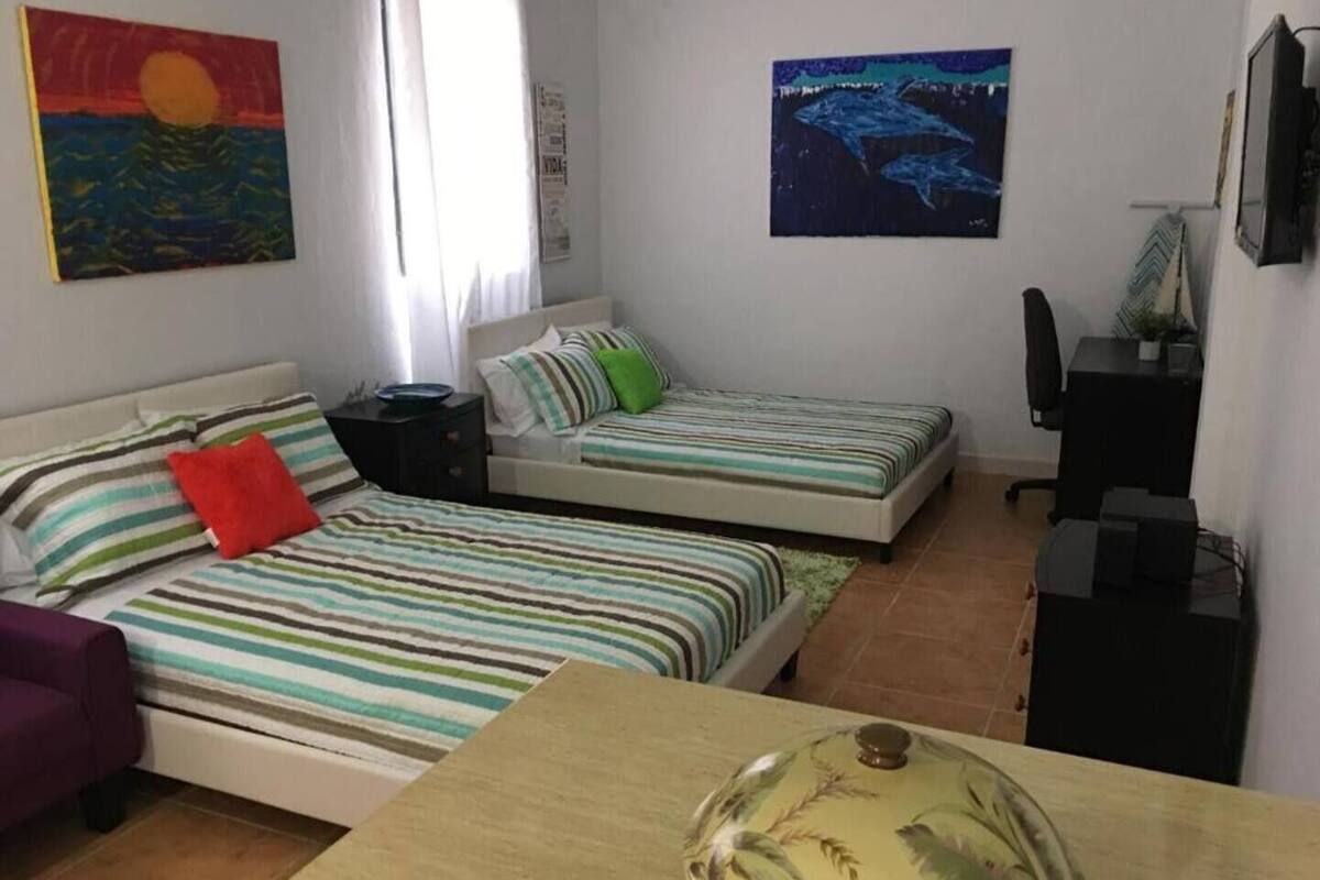 A bedroom with two beds, a desk, a chair, and a TV.
