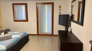 Hotelkamer met een bed, een televisie, een dressoir en een schuifpui naar een balkon.