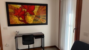 Een kamer met een bureau, stoel en een groot abstract schilderij aan de muur.
