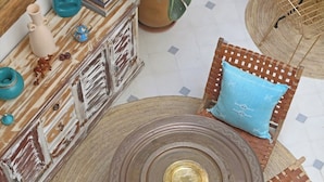 Una mesa redonda con un adorno central, rodeada por cuatro sillas tejidas con cojines azules.
