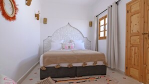 Un dormitorio con una cama, una puerta de madera y una ventana con cortinas.
