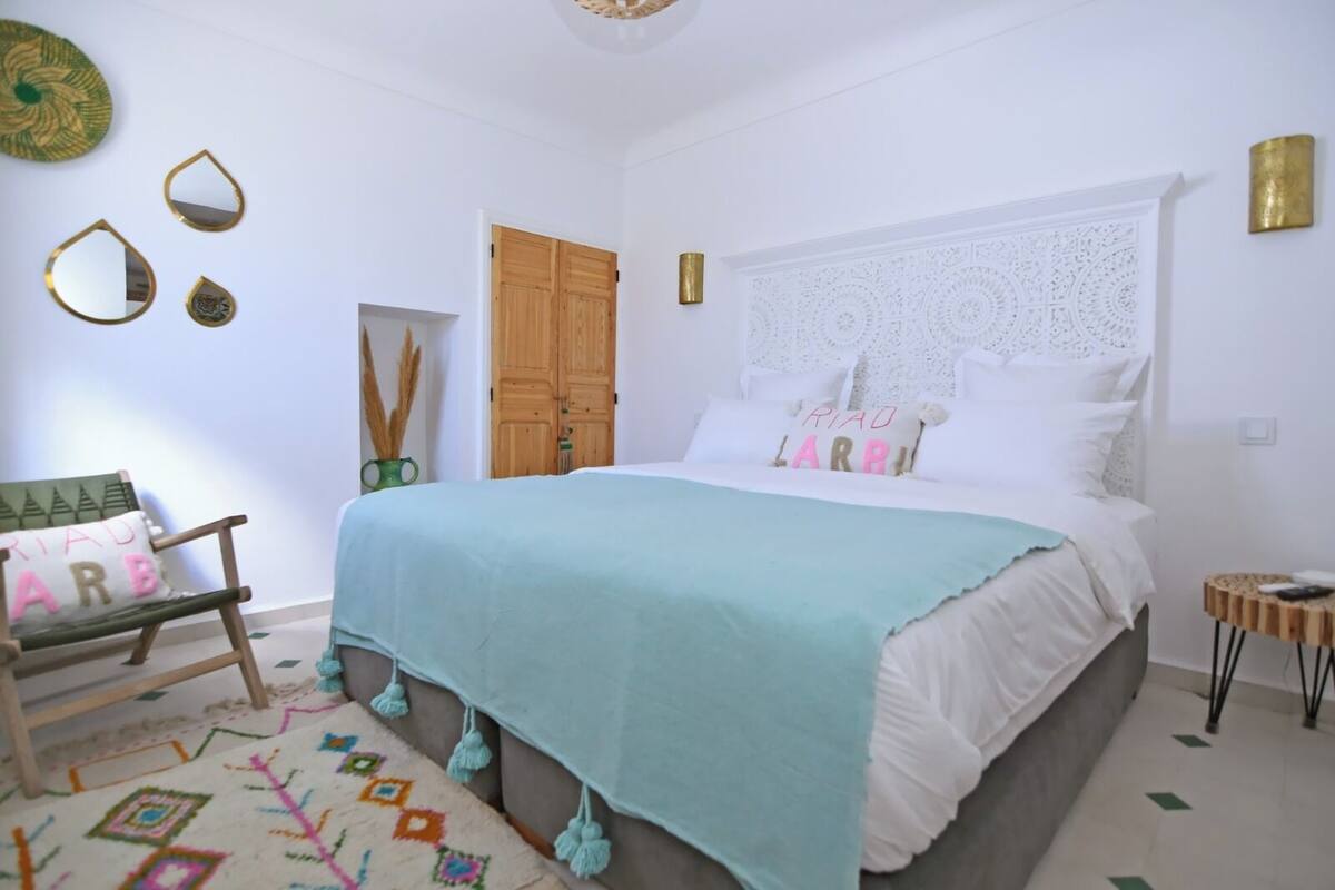 A bedroom with a bed, a chair, a small table, and decorative items on the walls.