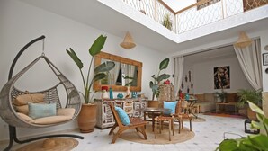 Un salón amplio con una silla colgante, muebles de madera y plantas en macetas.