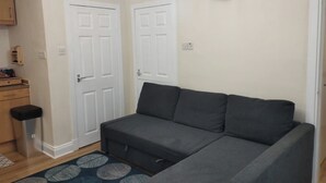 A living room with a grey sofa, a patterned rug, and a wall clock. - Central Edinburgh Flat Sleep 6, Minutes From old Town (Edinburgh)
