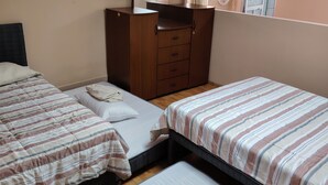 A hotel room with two beds, a wooden wardrobe, a mirror, and a window with curtains. - Enjoyable house with shared bathroom WiFi  in charming Huancayo (Huancayo)
