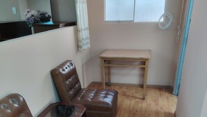 A small, cozy room with a brown leather sofa, a wooden coffee table, and a small table with a lamp. There is a window with a curtain, a wooden floor, and a small table with a vase of flowers. - Enjoyable house with shared bathroom WiFi  in charming Huancayo (Huancayo)