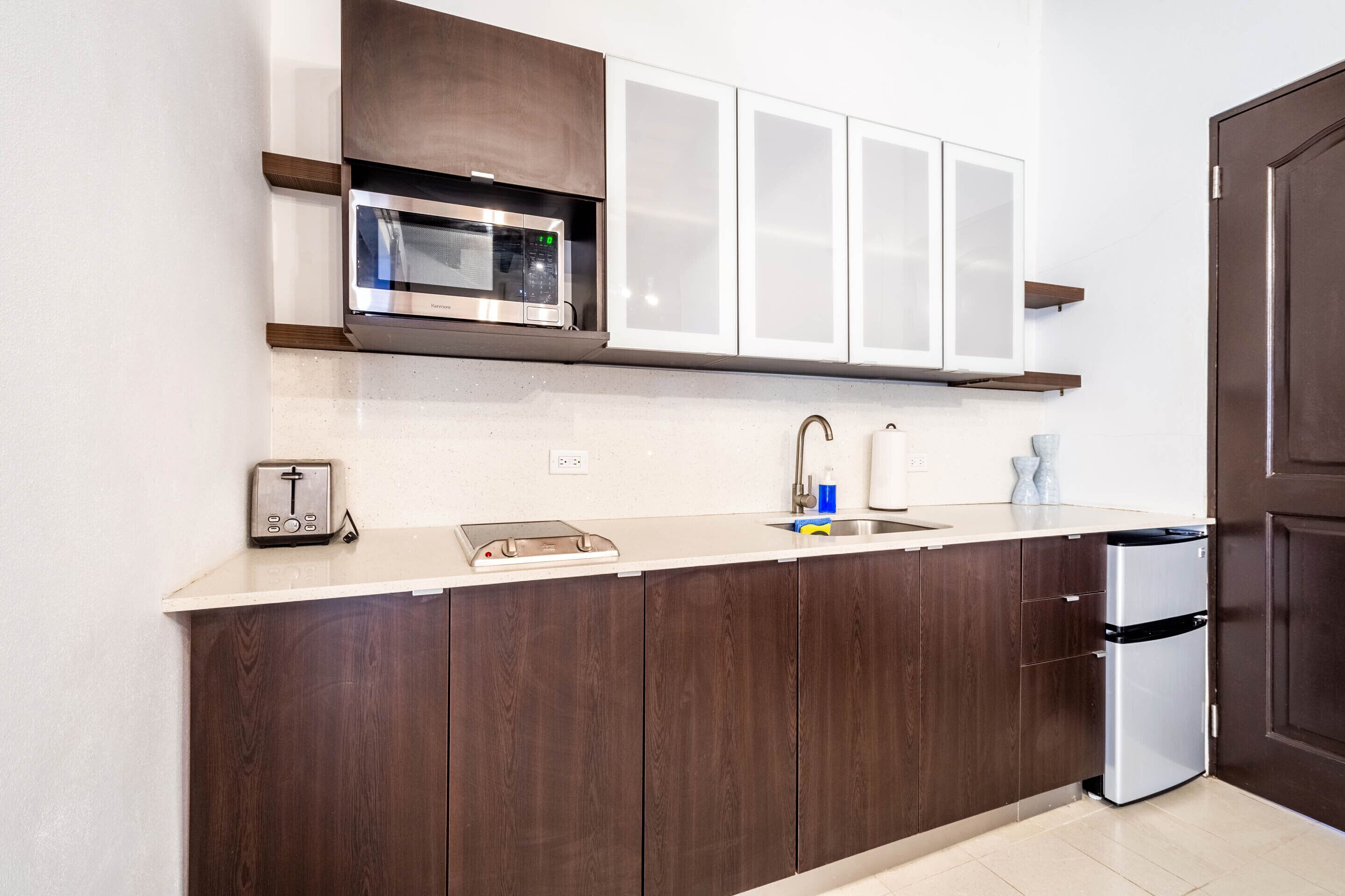 Uma cozinha moderna com micro-ondas embutido, torradeira e máquina de lavar louça em aço inoxidável.