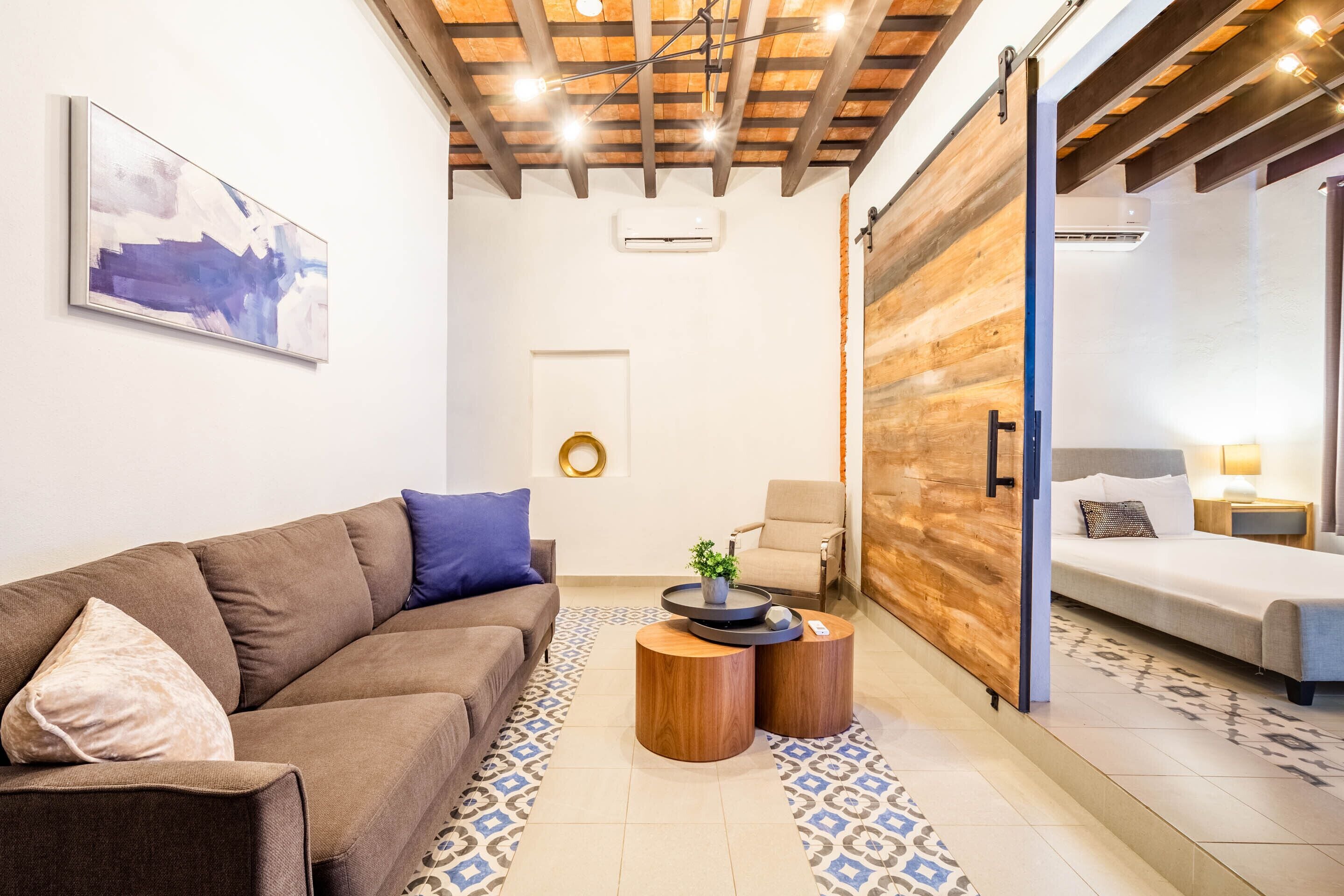 A modern living room with a brown sofa, a small wooden coffee table, and a patterned rug.