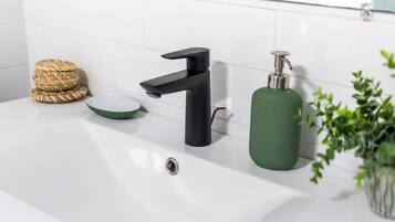 A bathroom sink with a modern faucet, a soap dispenser, and a small bowl.