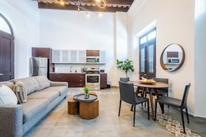 Una cocina moderna con electrodomésticos de acero inoxidable, un comedor con mesa y sillas de madera, y una sala de estar acogedora con sofá y una mesita de centro.
