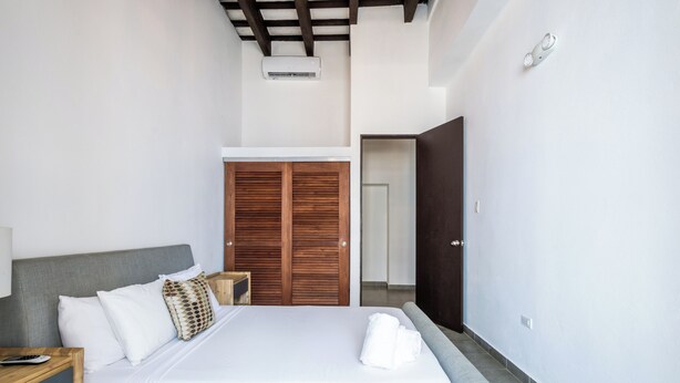 Une chambre moderne avec un lit, une armoire en bois et une porte donnant sur une autre pièce.