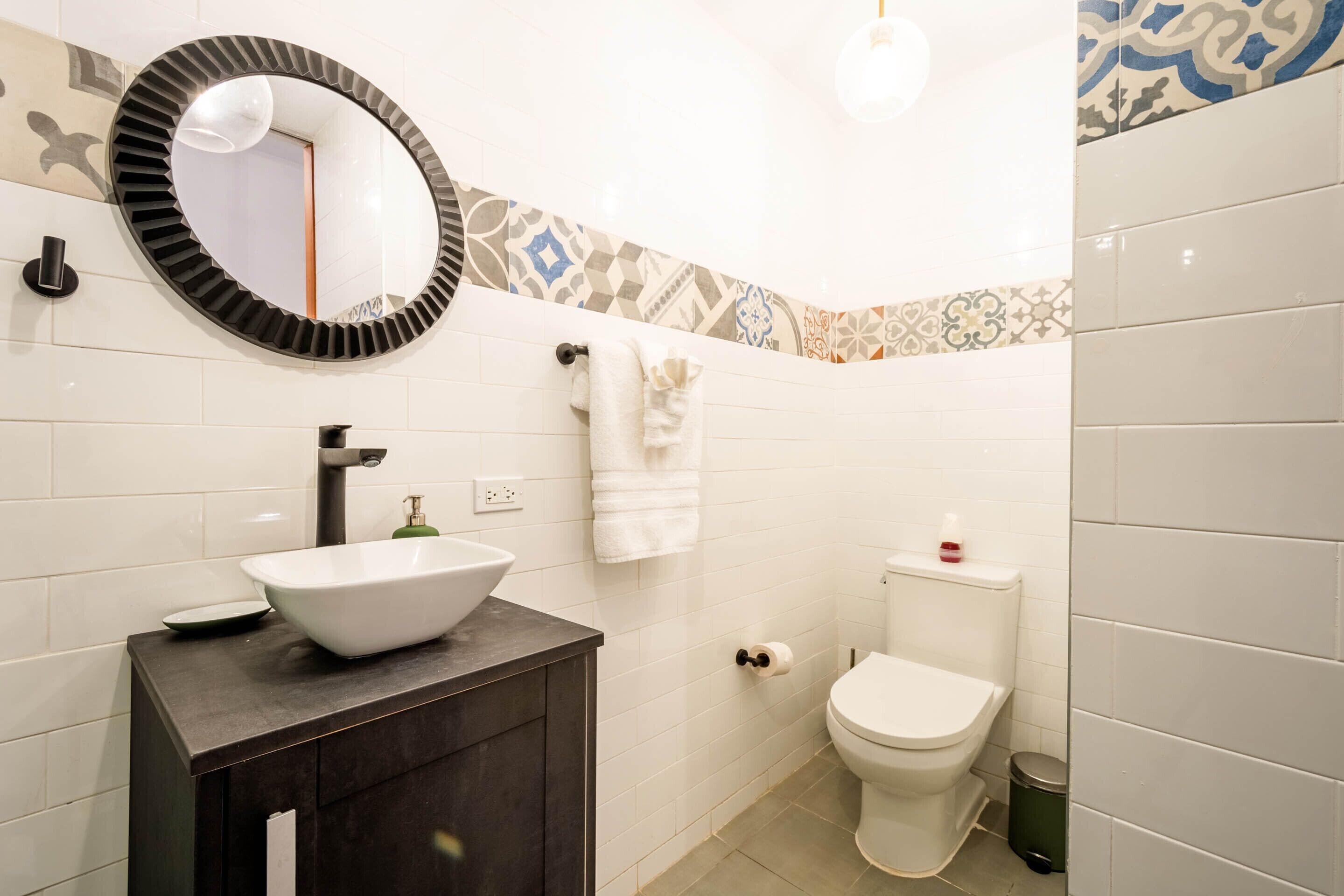 Un baño con lavamanos blanco, inodoro y espejo.