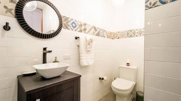 Un baño con lavamanos blanco, inodoro y espejo.