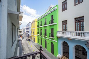 A narrow street with colorful buildings, a pedestrian, and a parked motorcycle.