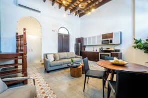Una sala de estar moderna con sofá, mesa de comedor y área de cocina con electrodomésticos.