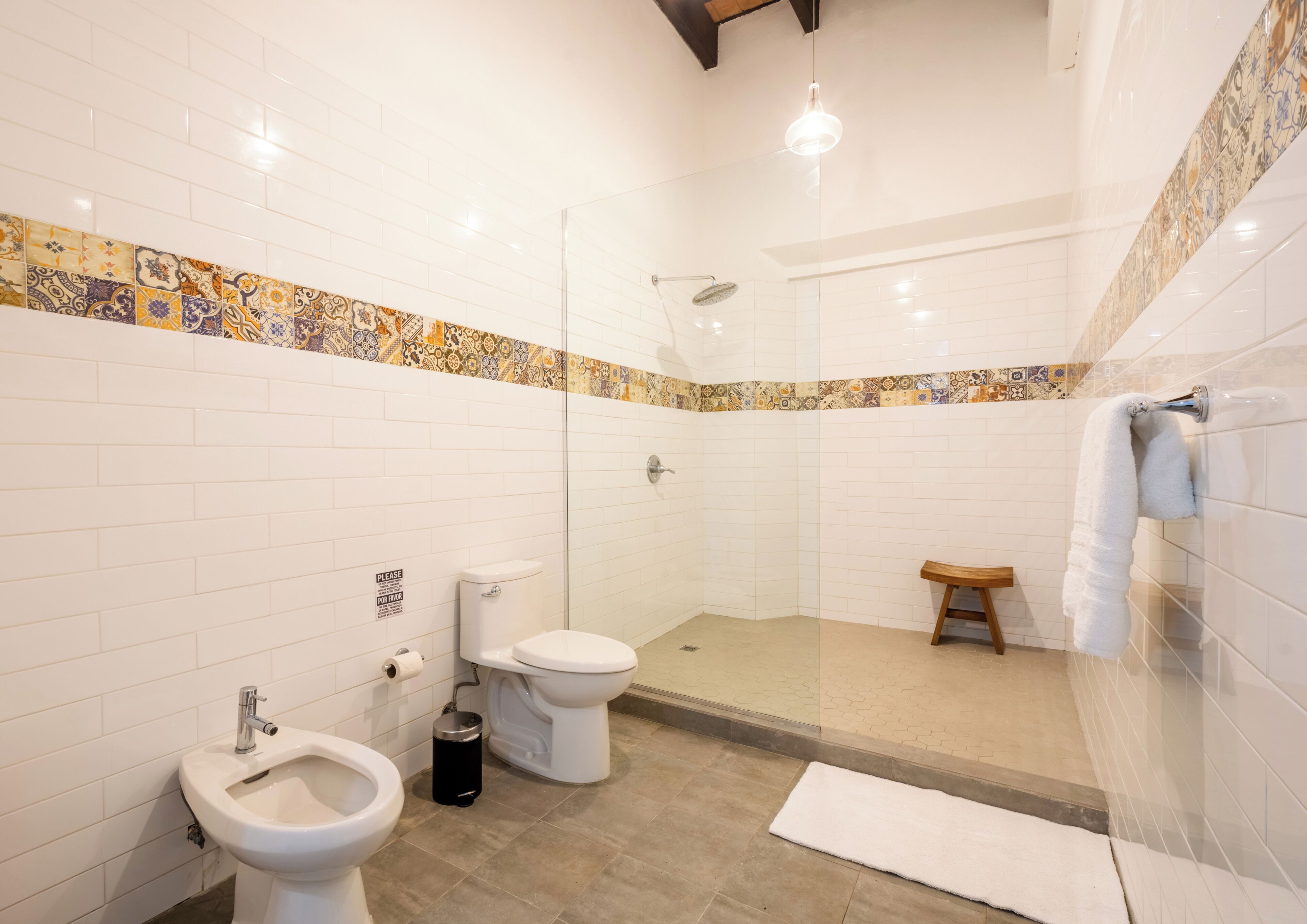 Un baño con ducha, inodoro, bidé y un perchero para toallas.