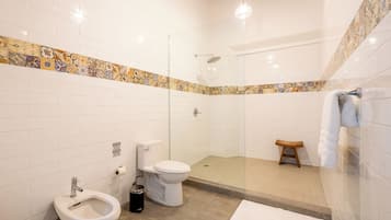 Un baño con ducha, inodoro, bidé y un perchero para toallas.