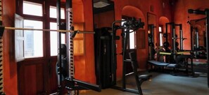 A gym with various exercise equipment, a bench, and a window with a view. - Casa Las Ruinas Boutique Hotel (San Juan)