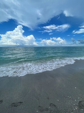 Une plage avec une eau d’un bleu limpide et un rivage sablonneux.