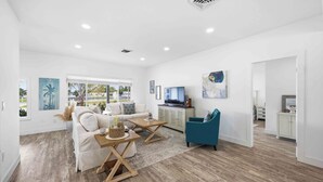 A spacious living area with a white sofa, a coffee table, and a television. - Heated Pool · Private Fire Pit · 3 Min to Beach -Manasota Key Gem 3/3 Home (Englewood)