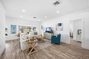 A spacious living area with a white sofa, a coffee table, and a television.