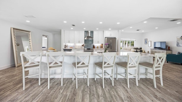 A modern kitchen with white cabinetry, a central island with bar stools, and a large window. - Heated Pool · Private Fire Pit · 3 Min to Beach -Manasota Key Gem 3/3 Home (Englewood)