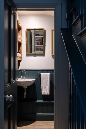 A narrow hallway leading to a bathroom with a sink, mirror, and towel rack. - William Mews by onefinestay (London)